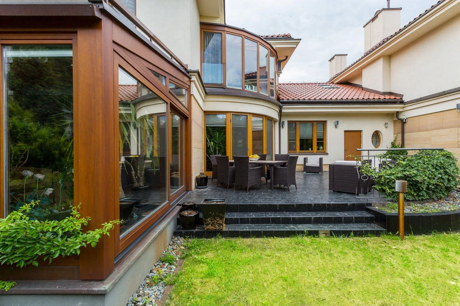 Aluminum sliding doors open onto a landscaped garden with a timber pergola