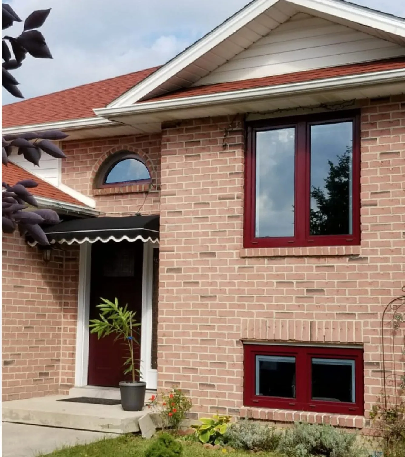 Brick house with deep-red clad tilt-and-turn windows and an arched transom over the entrance