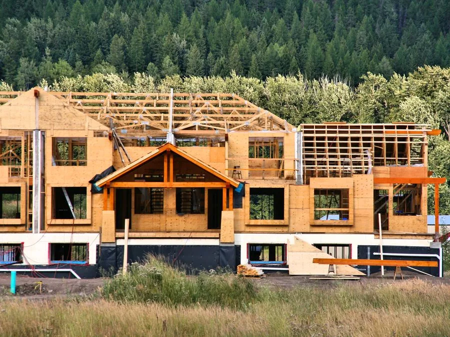 Wood-frame multi-family building under construction with window openings framed and ready for glazing